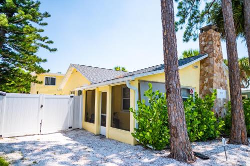 a yellow house with a white fence and trees at Sun-Drenched 1BR Apt - 5min walk to Beach in Clearwater Beach