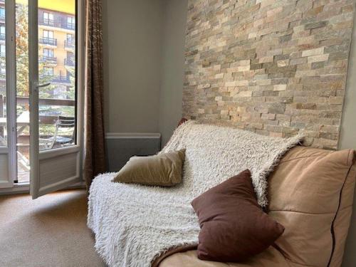 - une chambre avec un mur en briques et un lit avec des oreillers dans l'établissement Studio 4 Pers, Balcon Sud, Proche Commerces et Téléski, Risoul 1850 - FR-1-330-578, à Risoul