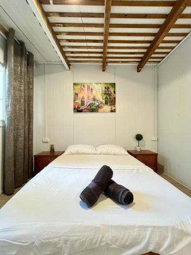 a bedroom with a white bed with a rolled up towel on it at Ramban Emerald in Haifa