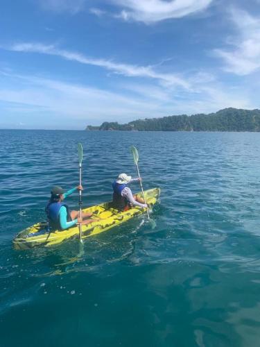 two people are sitting on a yellow kayak in the water at La Sirena Playa Jacó in Jacó