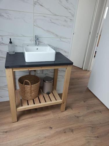 ein Badezimmer mit einem Waschbecken auf einem Tisch und einem Korb in der Unterkunft Appartement 2 chambres in Lesneven