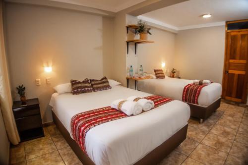 a hotel room with two beds with towels on them at RUMIQOLQA Machupicchu Hotel in Machu Picchu