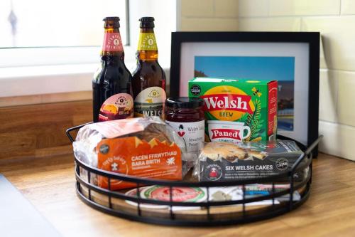 a basket filled with food and beer on a table at Steel Town Lodge - Comfy Home in Port Talbot with Hot Tub & Dart Board in Port Talbot