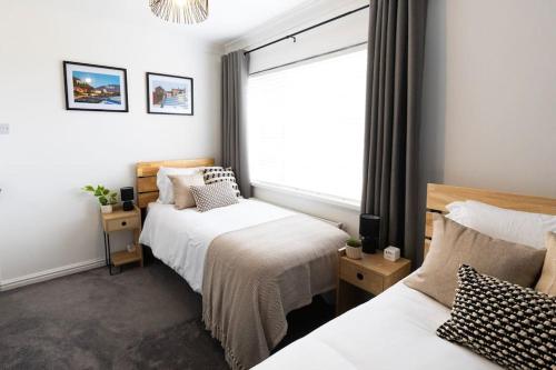 um quarto com 2 camas e uma janela em Steel Town Lodge - Comfy Home in Port Talbot with Hot Tub, Sky Sports & Dart Board em Port Talbot