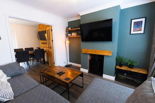 a living room with a couch and a tv on a wall at Steel Town Lodge - Comfy Home in Port Talbot with Hot Tub & Dart Board in Port Talbot