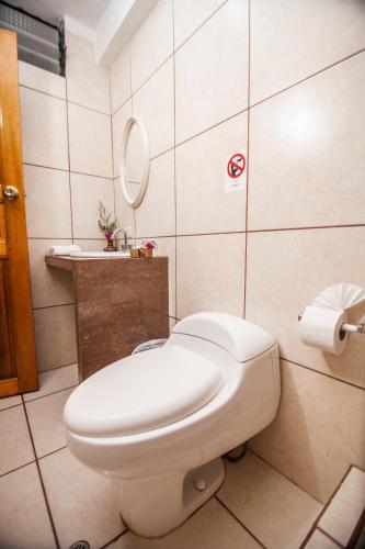 a bathroom with a white toilet and a mirror at RUMIQOLQA Machupicchu Hotel in Machu Picchu