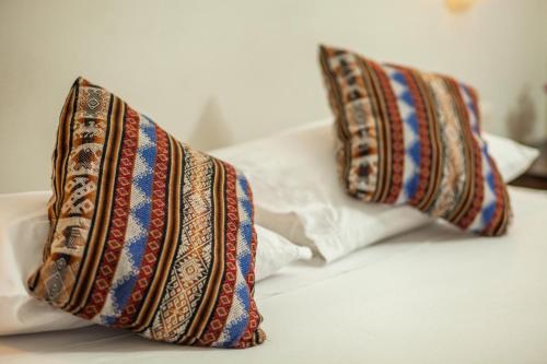 two pillows are sitting on a bed at RUMIQOLQA Machupicchu Hotel in Machu Picchu