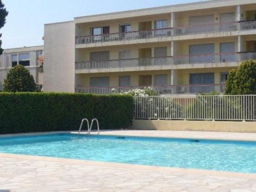 une piscine devant un immeuble dans l'établissement Appartement avec Piscine et Terrasse, Proche Plage - 4 Couchages, Parking, Animaux Acceptés - FR-1-251-808, au Lavandou