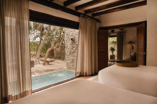 a bedroom with a view of a pool through a window at Aldea Canzul Tulum in Tulum