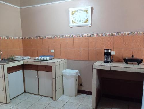 a kitchen with a sink and a clock on the wall at Cabinas Miramar, una casa SOLO para ti in San Isidro