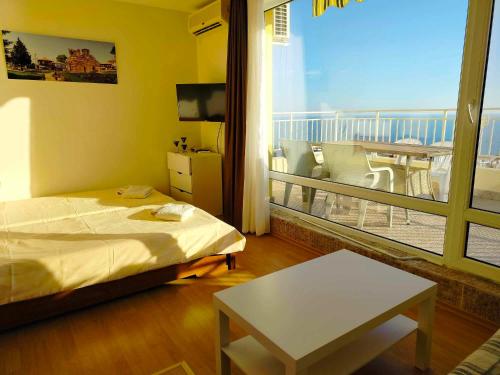 a bedroom with a bed and a balcony with a table at Golden Sea View in Sveti Vlas
