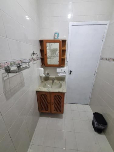 a white bathroom with a sink and a door at Villa Fátima Hostel GRU in Guarulhos