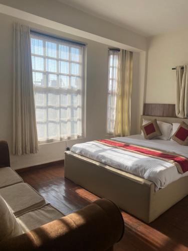 um quarto com uma cama, um sofá e janelas em grape apartments em Kathmandu