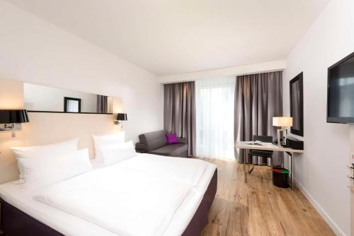 a hotel room with a large white bed and a desk at Scandic Berlin Kurfürstendamm in Berlin