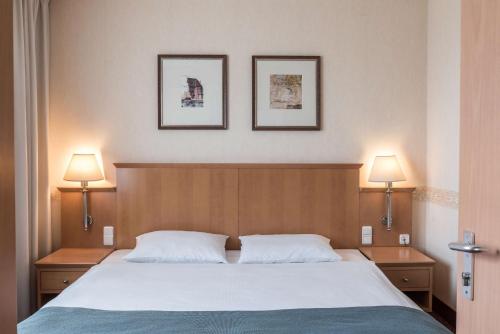 een slaapkamer met een bed en twee foto's aan de muur bij Scandic Gdańsk in Gdańsk