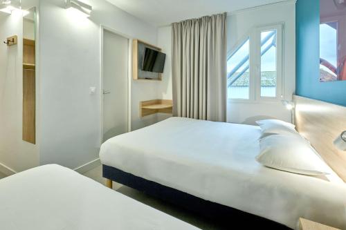 a hotel room with two beds and a window at Kyriad Direct Moulins Sud - Yzeure in Yzeure