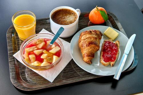 a tray with a breakfast of croissant and fruit and coffee at Kyriad Direct Moulins Sud - Yzeure in Moulins