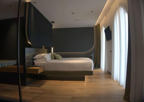 ein Schlafzimmer mit einem Bett und einem großen Fenster in der Unterkunft Hotel Al Caminetto WorldHotels Crafted Adults Only in Torri del Benaco