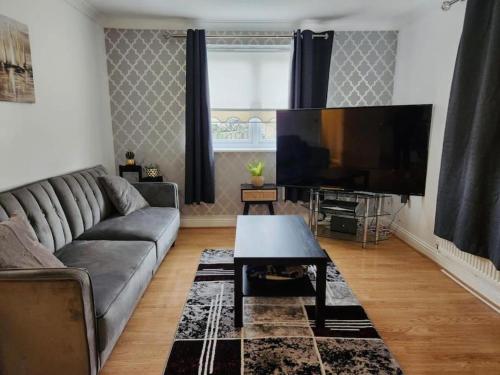 a living room with a couch and a flat screen tv at Spacious Ground floor 2 bedroom 2 Bathroom Flat in Hatfield near Hertfordshire University Private Car Park Sleeps 5-6 in Hatfield