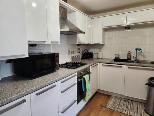 a kitchen with white cabinets and a stove top oven at Spacious 2 bedroom 2 Bathroom Flat in Hatfield near Hertfordshire University with Private Car Park Sleeps 5-6 in Hatfield