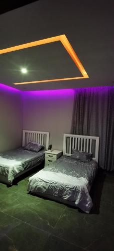 2 camas en una habitación con luces moradas en منتجع سمايل, en Al-Qurayat