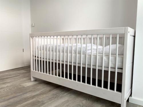 - un lit bébé blanc dans une chambre aux murs blancs dans l'établissement Haus "Friesland 10", Am Alten Deich 15c, à Dangast