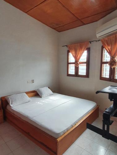 Bett in einem Zimmer mit 2 Fenstern und einem Schreibtisch in der Unterkunft Delalie Hotel in Palimé