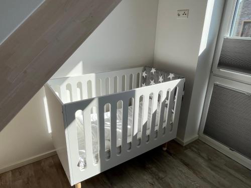 - un lit bébé blanc dans une chambre située à côté d'une fenêtre dans l'établissement Nordsee Park Haus Friesland 7 P113, à Dangast