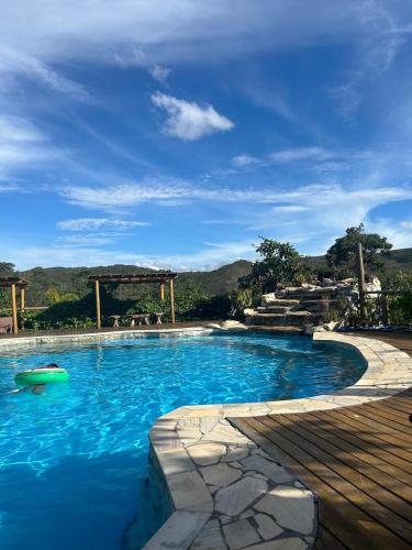 a swimming pool with blue water and a wooden deck at Pousada Serra Morena in Serra do Cipo