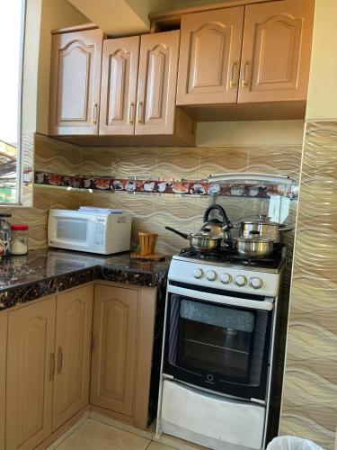 a kitchen with a stove and a microwave at MISKI PUÑUY - Dulces sueños HOSPEDAJE in Cusco
