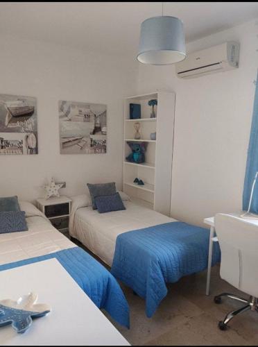 een slaapkamer met 2 bedden met blauwe lakens en een bureau bij KBM-2 in Cádiz