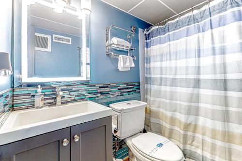 uma casa de banho com um WC, um lavatório e um espelho. em Assateague House 205 em Ocean City