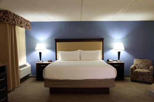 a bedroom with a bed and a chair and two lamps at Radisson Hotel Schaumburg in Schaumburg
