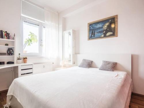 a white bedroom with a white bed and a window at Cosy 2 bedroom flat close to the town with parking in Bratislava