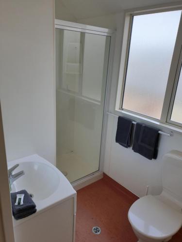 baño con lavabo y aseo y ventana en Northcote Motor Lodge, en Christchurch