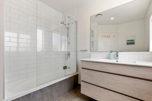 a white bathroom with a sink and a shower at Modern Sanctuary on the reserve in Auckland