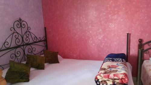 a bedroom with a bed and a pink wall at Kasabah Senhaji in Moulay Idriss Zerhoun