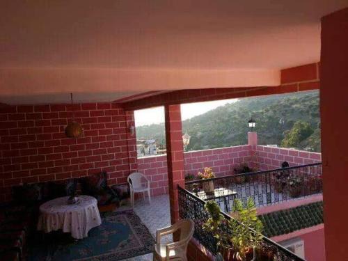 a balcony with a table and a brick wall at Kasabah Senhaji in Moulay Idriss Zerhoun