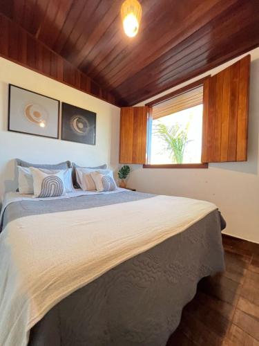 a bedroom with a large bed with a window at Paraíso Capitólio Suítes Pousada in Capitólio