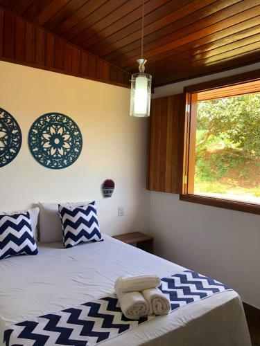 a bedroom with a bed with blue and white pillows and a window at Paraíso Capitólio Suítes Pousada in Capitólio