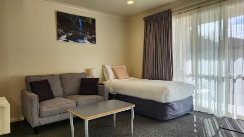 Habitación de hotel con cama y sofá en Northcote Motor Lodge, en Christchurch