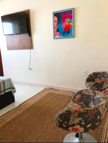 a living room with two chairs and a flat screen tv at Suite master in Rio Branco