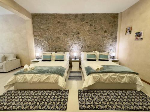 a bedroom with two beds and a stone wall at Loft Mueganos III en Val´Quirico in Santeagueda