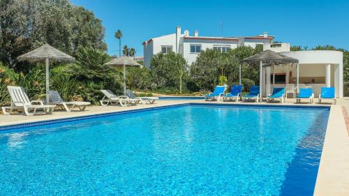 a swimming pool with blue chairs and umbrellas at Casas do Ramalhete in Luz