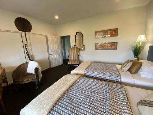 a bedroom with two beds and a chair at Chateau Pritchard in Springston