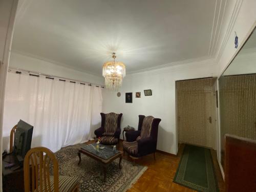 a living room with two chairs and a chandelier at Mahitab music in Cairo