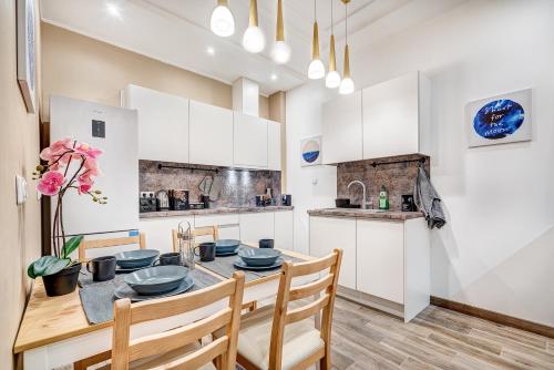 a kitchen with white cabinets and a table and chairs at Deluxe Hostel with Sauna, TV, Bidet, Kitchen & Parking in Kaunas