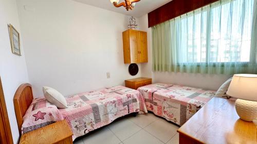 a bedroom with two beds and a window at REYNA Playa de Gandía - Alquiler solo a familias in Los Mártires