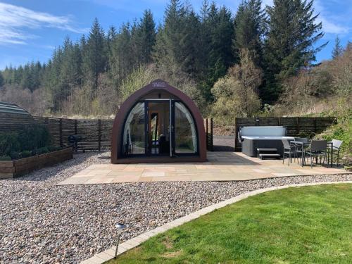 um gazebo num jardim com uma mesa e cadeiras em Red Squirrel Pod with Hot Tub em Oban