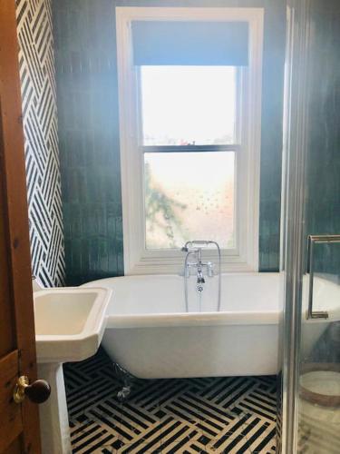 a bathroom with a tub and a window and a sink at Llangollen Townhouse 4 bedroom in Llangollen